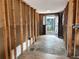 Hallway featuring stone floors and exposed stud walls, leading to a glass panel front door at 13930 King Ave, Hudson, FL 34669
