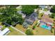 Aerial view of a property with a screened pool, lush landscaping and solar panels on the roof at 1509 Coachlight Way, Dunedin, FL 34698