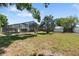 The lush backyard features mature trees, a screened-in lanai, and is perfect for outdoor activities at 1509 Coachlight Way, Dunedin, FL 34698