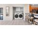 Bright laundry area with white washer and dryer, stylish chairs, and an opening to the kitchen at 1509 Coachlight Way, Dunedin, FL 34698