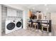 Bright laundry area with white washer and dryer, stylish chairs, and an opening to the kitchen at 1509 Coachlight Way, Dunedin, FL 34698
