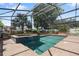 Screened in pool and hot tub with brick deck and lush landscaping at 1509 Coachlight Way, Dunedin, FL 34698