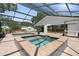 Screened in pool and hot tub with brick deck surrounded by lush landscaping at 1509 Coachlight Way, Dunedin, FL 34698