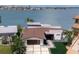 Aerial view of a modern waterfront home with a private dock, manicured lawn, and lush landscaping at 16496 Redington Dr, Redington Beach, FL 33708