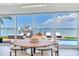 Dining area with view of boat dock, pool, and waterfront with modern dining table and chairs at 16496 Redington Dr, Redington Beach, FL 33708