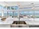 Kitchen island with marble countertop and stainless steel sink overlooking an open living area with waterfront views at 16496 Redington Dr, Redington Beach, FL 33708