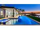 A luxurious pool and spa with modern design, outdoor seating, and a dock overlooking the serene waterfront at twilight at 16496 Redington Dr, Redington Beach, FL 33708