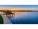 Scenic waterfront view featuring a private boat dock and picturesque sunset over the open water at 16496 Redington Dr, Redington Beach, FL 33708