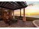 Stunning backyard patio featuring a pergola, lounge chairs, and breathtaking waterfront views during a vibrant sunset at 2402 Baywood W Dr, Dunedin, FL 34698