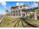 Expansive backyard with lush landscaping, covered pergola, and tiered balconies in this luxury home at 2402 Baywood W Dr, Dunedin, FL 34698