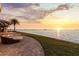 A luxurious backyard features waterfront views, a cozy outdoor lounge area, and manicured lawn at 2402 Baywood W Dr, Dunedin, FL 34698