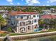 A beautiful waterfront home is shown with a private dock, lush landscaping, and multi-level balconies at 2402 Baywood W Dr, Dunedin, FL 34698