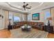 Spacious living room with leather sofa, water views, large windows and a ceiling fan at 2402 Baywood W Dr, Dunedin, FL 34698