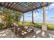 An outdoor lounge area features a pergola, lounge chairs, and views of the water at 2402 Baywood W Dr, Dunedin, FL 34698
