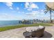 Inviting patio with lounge seating, a palm tree, and stunning views of the water and the private dock at 2402 Baywood W Dr, Dunedin, FL 34698