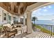 An expansive patio area boasts outdoor seating, wrought iron railings, and stunning views of the waterfront and the palm tree at 2402 Baywood W Dr, Dunedin, FL 34698