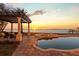 Beautiful backyard oasis featuring a luxurious pool, hot tub, covered lounge area, and serene waterfront views at 2402 Baywood W Dr, Dunedin, FL 34698