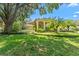 Well-maintained front yard with lush green lawn, mature trees, and manicured landscaping accentuating this yellow home's facade at 3022 Forest Club Dr, Plant City, FL 33566