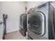 A modern laundry room features new front loading washer and dryer, tile floors, and wall mounted storage at 31649 Tansy Bnd, Wesley Chapel, FL 33545