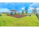 Community playground with slides and swings, set against a backdrop of green grass and beautiful blue skies at 31649 Tansy Bnd, Wesley Chapel, FL 33545