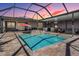 Inviting screened-in pool area featuring a clear blue swimming pool, hot tub, and outdoor kitchen at 31649 Tansy Bnd, Wesley Chapel, FL 33545