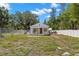 View of a cozy single-story house from the yard, surrounded by trees and fencing at 3310 70Th N Ave, St Petersburg, FL 33702