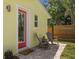 Exterior view showcasing the charming exterior of home with a red door and cozy seating area at 617 Scotland St, Dunedin, FL 34698