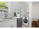 All-white kitchen featuring modern cabinets, stainless steel appliances, and in-unit washer and dryer at 617 Scotland St, Dunedin, FL 34698