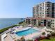 A pool is surrounded by lounge chairs, palm trees, and condos with an ocean view at 6269 Palma Del Mar S Blvd # 112, St Petersburg, FL 33715