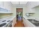 Efficient galley kitchen featuring white appliances and cabinetry, with a view to the dining room at 650 Pinellas Point S Dr # 216, St Petersburg, FL 33705