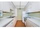 Galley kitchen with white appliances and cabinets, offering functional space and lots of counter space at 650 Pinellas Point S Dr # 216, St Petersburg, FL 33705