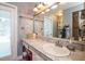 Well-lit bathroom featuring tiled walls, a neutral-toned countertop, and a large mirror with vanity lights at 6505 Bimini Ct, Apollo Beach, FL 33572