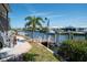 Waterfront view featuring a dock, boat, and lush landscaping under a bright, sunny sky at 6505 Bimini Ct, Apollo Beach, FL 33572