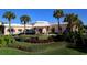 Inviting clubhouse entrance surrounded by lush landscaping and mature palm trees in a desirable community at 6650 Sunset Way # 118, St Pete Beach, FL 33706