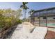 View of the screened-in pool area from the yard, with palm trees and landscaping at 7906 Bayshore Dr, Seminole, FL 33776
