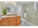 Bathroom features a wood vanity, round mirror, and tiled shower at 7906 Bayshore Dr, Seminole, FL 33776