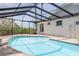 Sparkling in-ground pool inside screened enclosure, with access steps at 7906 Bayshore Dr, Seminole, FL 33776