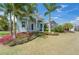 Charming front yard featuring lush landscaping, mature palm trees, and a beautiful light blue two-story home at 814 Manns Harbor Dr, Apollo Beach, FL 33572