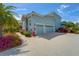 Three-car garage with light blue doors and a paver driveway, surrounded by lush tropical foliage at 814 Manns Harbor Dr, Apollo Beach, FL 33572