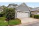 Two-car garage with white door in front of a gray two-story home with green grass at 9106 Crystal Commons Way, Tampa, FL 33626