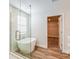 Luxurious bathroom featuring a freestanding tub, a glass-enclosed shower, and wood-look flooring at 10025 Surrey Rose Dr, San Antonio, FL 33576