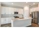 Open white kitchen with a center island, stainless steel appliances, and ample cabinet space at 10025 Surrey Rose Dr, San Antonio, FL 33576
