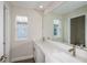 Bright bathroom features double sinks with quartz countertop, a large mirror, and modern fixtures at 10037 Surrey Rose Dr, San Antonio, FL 33576