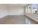 Bright, empty living room with three large windows and hardwood flooring at 10037 Surrey Rose Dr, San Antonio, FL 33576