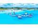Stunning aerial view of a community waterpark with inflatable obstacle course, sandy beach, and clear blue water at 10049 Surrey Rose Dr, San Antonio, FL 33576