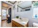 Bathroom featuring tile floors, wooden vanity, a framed mirror, and a window, alongside an exterior exit at 11831 104Th Ln, Largo, FL 33773