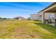 Spacious backyard with green grass and view of the house and extended covered porch at 12107 Nouveau Ave, Spring Hill, FL 34610