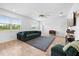 Bright living room with large windows, wood floors, and a comfortable, stylish, green sofa at 12107 Nouveau Ave, Spring Hill, FL 34610