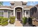 Inviting home entrance with an arched entryway, decorative lighting, and lush landscaping creating curb appeal at 14434 Scottburgh Glen Dr, Wimauma, FL 33598
