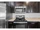 Close-up of a kitchen with granite countertops and stainless steel appliances, including a microwave and range at 14434 Scottburgh Glen Dr, Wimauma, FL 33598